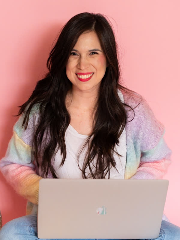 Ashley, smiling with her laptop and a pile of printables